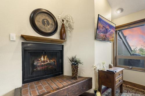 a living room with a fireplace with a clock on the wall at Country Club Condo in Flagstaff in Flagstaff