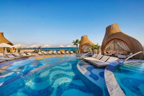 a swimming pool with chairs and umbrellas at a resort at Waldorf Astoria Doha Lusail in Doha