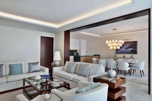 a living room with white furniture and a dining room at Waldorf Astoria Doha Lusail in Doha