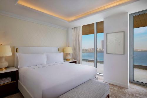 a bedroom with a white bed and a large window at Waldorf Astoria Doha Lusail in Doha
