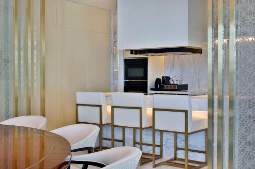 a kitchen with a bar with white chairs and a table at Waldorf Astoria Doha Lusail in Doha