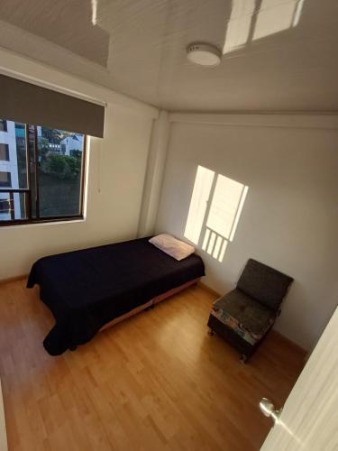a bedroom with a bed and a chair and a window at Amplia Habitación En El Cable in Manizales