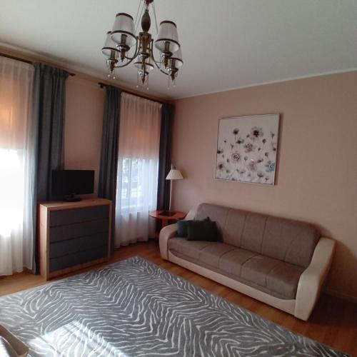 a living room with a couch and a television at Jūras Brīze in Ventspils