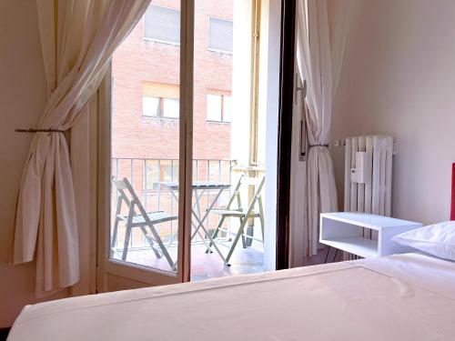 1 dormitorio con 1 cama y ventana con balcón en The Boutique Houses Milan - Repubblica - Central Station, en Milán