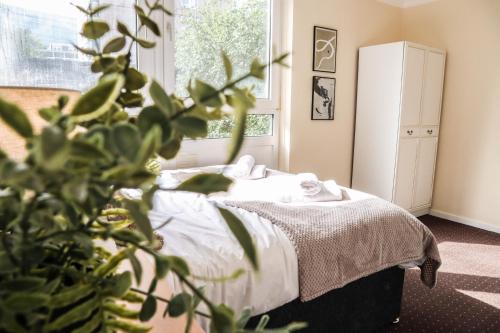 ein Schlafzimmer mit einem Bett und eine Pflanze im Vordergrund in der Unterkunft Cosy property right by WARREN STREET station! FREE WIFI! in London