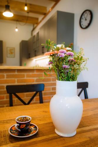 a white vase with flowers on a table with a cup of coffee at Chalupa Mahouš 19 in Mahouš