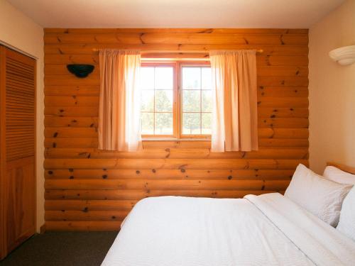 um quarto com uma cama branca e uma janela em Kilomètre 42 em Val-David