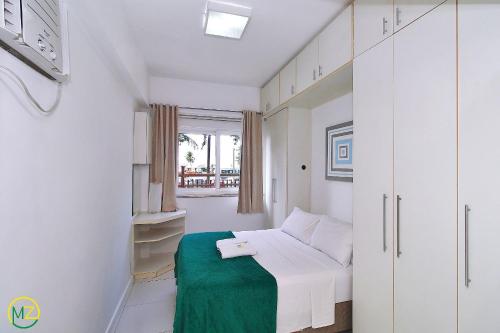 Habitación blanca con cama y manta verde en Studio na Avenida Atlantica de frente para a praia, en Río de Janeiro