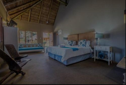 a large bedroom with a bed and a chair at Aero Airport Lodge in Kempton Park