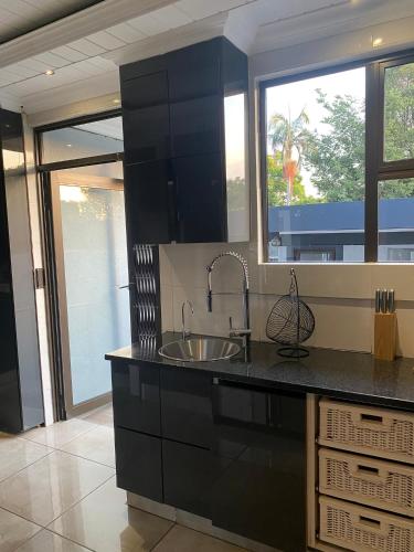 a kitchen with a sink and a large window at Bridgelamour Guest House in Hartbeespoort