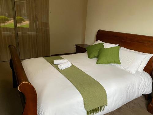 Una cama con almohadas verdes y blancas. en Bridgelamour Guest House, en Hartbeespoort