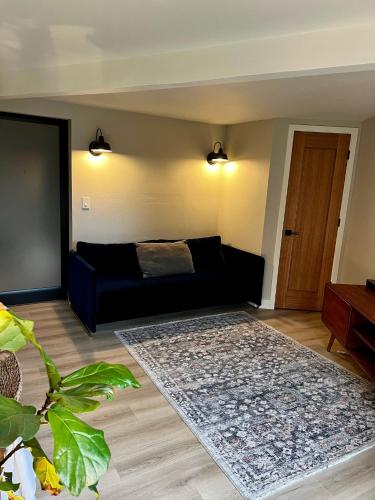 a living room with a black couch and a rug at NEW Modern apt w/pool & hot tub in nature in Thousand Oaks