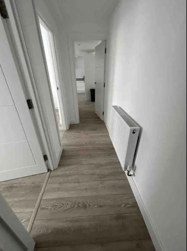 an empty hallway with white walls and wooden floors at 2 Bedroom Luxury Appartment in Finchley