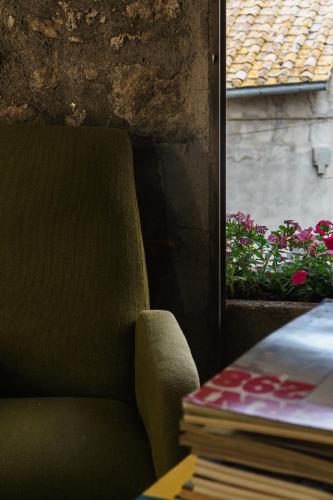 a green chair next to a window with a book at Inter Artes Prestige House and Luxury Suite in Viterbo