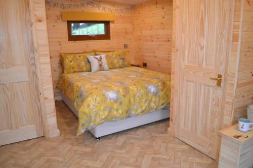 a bedroom with a bed in a wooden room at LetAway - The Warren Lodge at Ashes Farm in Settle