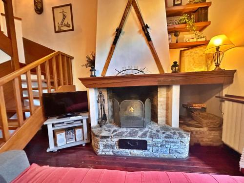 a living room with a stone fireplace with a tv at D2, Bordes d'Arinsal, Duplex Rustico con chimenea, Arinsal , zona Vallnord in Arinsal