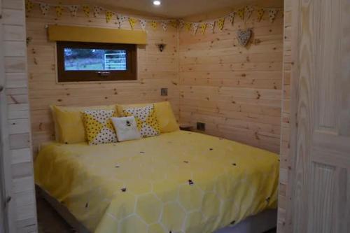 a bedroom with a yellow bed in a wooden wall at LetAway - The Hive Lodge at Ashes Farm in Settle