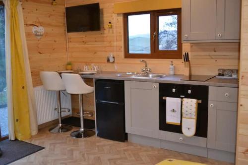 a kitchen with a sink and a counter with two stools at LetAway - The Hive Lodge at Ashes Farm in Settle