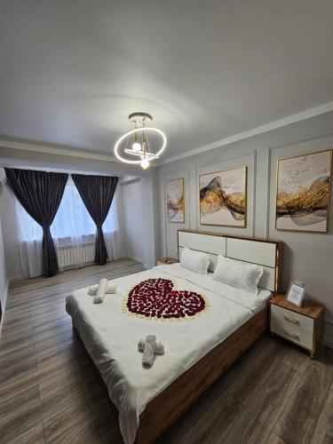 um quarto com uma grande cama branca e um cobertor vermelho em DeLuxe Apartments em Almaty