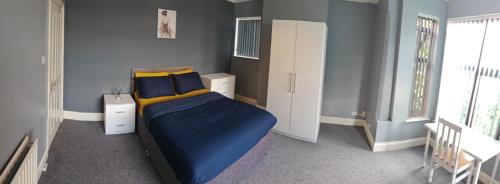 a bedroom with a bed with blue sheets and yellow pillows at Spacious large room 001 in Nottingham