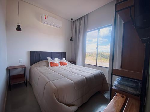 a bedroom with a bed with orange pillows and a window at Banglo in Alto Paraíso de Goiás