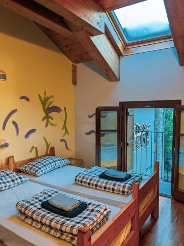 two beds in a room with a wall with a mural at Rifugio Aleve in Castello