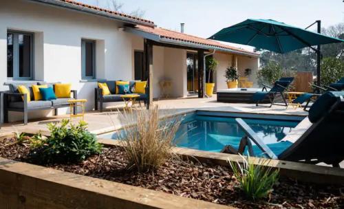 une maison avec une piscine et un parasol dans l'établissement La villa du lac Biscarosse, à Biscarrosse