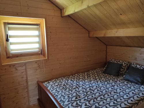 a bed in a log cabin with a window at Domek u Emi in Wilkasy