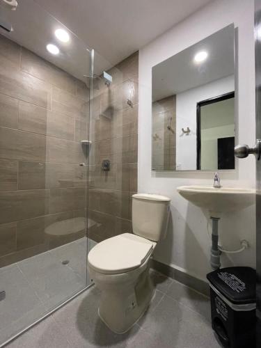 a bathroom with a toilet and a shower and a sink at Hotel De León Estadio in Medellín
