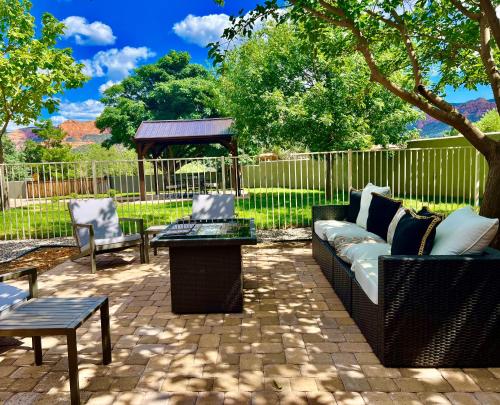 a patio with a couch and tables and a fence at Sedona Uptown Gem!Large yard w grass and shade trees! Views!! NEW! BARREL SAUNA!!! Close to trails, walk to Uptown Sedona, restaurants and shopping in Sedona