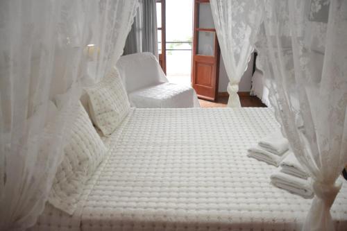a white bed with white curtains and a chair at Stefanos Katsaros Studios in Skala