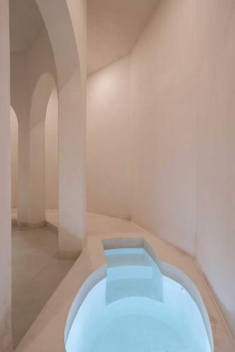 a hot tub in a white room with an arch at Anat Tantric Boutique Hotel in Tulum