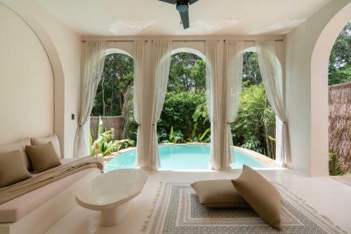 a living room with a swimming pool and windows at Anat Tantric Boutique Hotel in Tulum