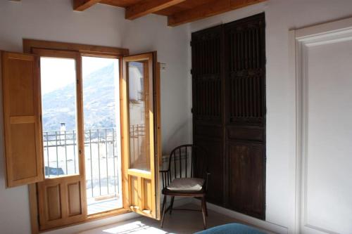 a room with a door and a chair and a balcony at Casa Las Alacenas, Bubión (La Alpujarra, Granada) in Bubión