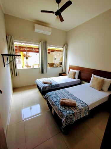 a bedroom with two beds and a ceiling fan at Pouso Oliveira Casa com ar condicionado in São João Batista do Glória
