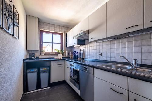 a kitchen with white cabinets and a sink at Nature Terminal Apartment - unterwegs zuhause in Steinenbronn