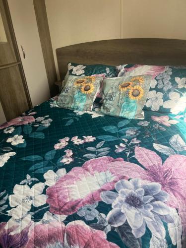 a bed with a floral quilt and two pillows on it at Haggerston castle caravan rental. Annie's den in Beal