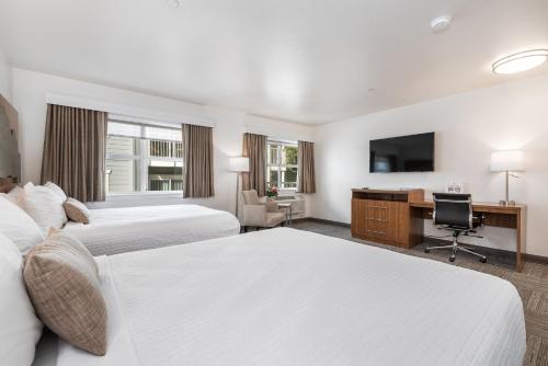 a hotel room with two beds and a desk and a television at Marshall Suites in Bainbridge