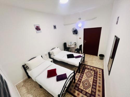 2 camas en una habitación con paredes blancas en Desert Moon, en Wadi Musa