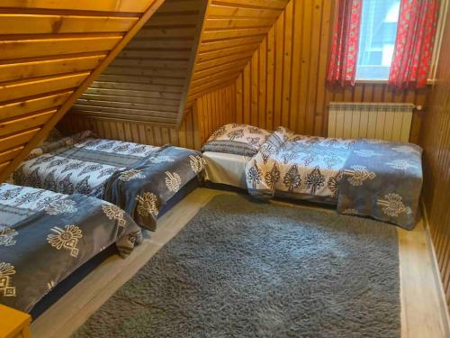 two beds in a room with wooden walls at Domki u Marii- agroturystyka in Bańska Niżna