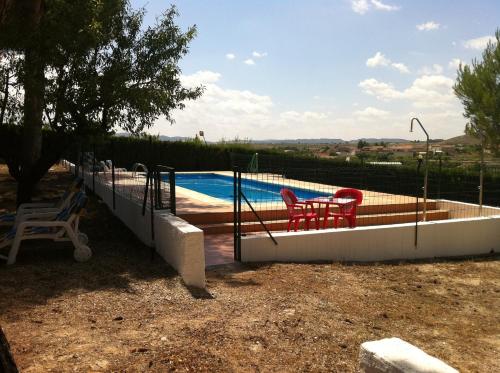 a swimming pool with two red chairs next to it at Hotel El Zorro in Barranda