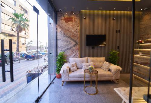 a living room with a couch and a tv on a wall at Gold's Pyramids Hotel in Cairo