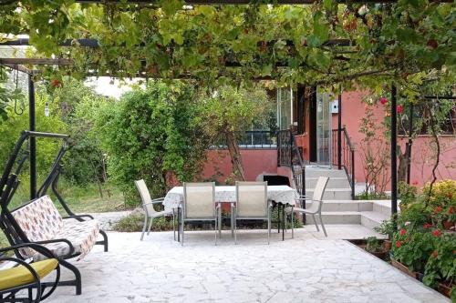 a patio with a table and chairs under a pergola at yeşillikler içinde bağ evi 