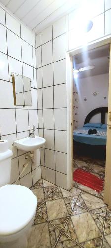 a bathroom with a toilet and a sink and a bed at Jurema Hostel in Itacaré