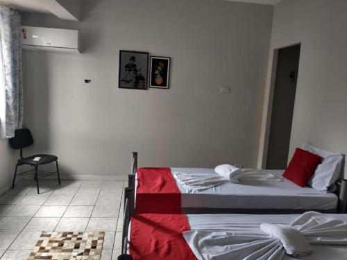 - une chambre avec 2 lits et une chaise dans l'établissement Pousada Flor de Mãe, à Volta Redonda