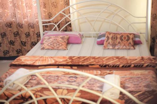 two beds with pillows on them in a bedroom at Emmas' Guest House in Kampala