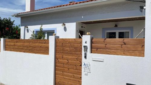 une maison blanche avec une clôture en bois devant elle dans l'établissement Vila Vale Guest House - Surf & Yoga, à Charneca