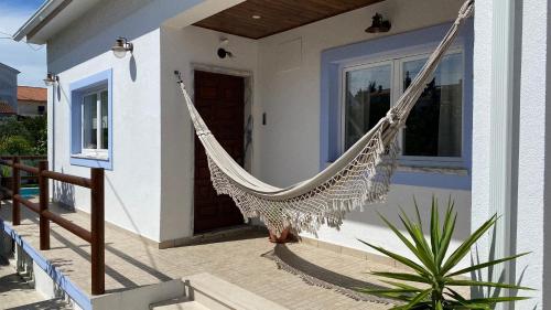 a hammock hanging from the side of a house at Vila Vale Guest House - Surf & Yoga in Charneca