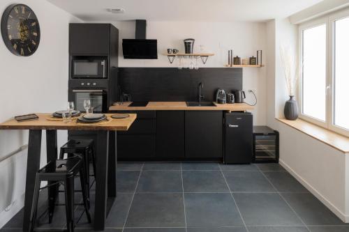 une cuisine avec des armoires noires et un comptoir avec une table dans l'établissement UNE PARENTHESE ARDENNAISE, à Charleville-Mézières