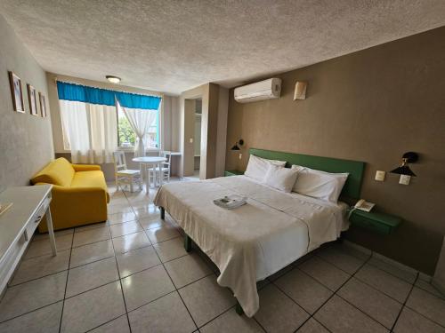 ポサ・リカ・デ・イダルゴにあるHotel Punto Poza Ricaのベッドと黄色い椅子が備わるホテルルームです。
